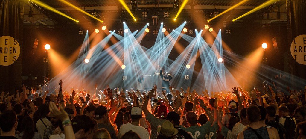 concert with people dancing and dynamic lights beaming down