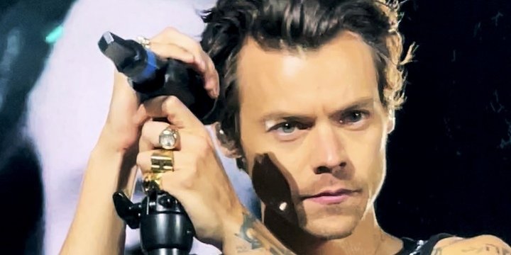 Harry Styles Wembley June 2022 (cropped) by Lily Redman is licensed under CC BY 2 0 man holding a microphone