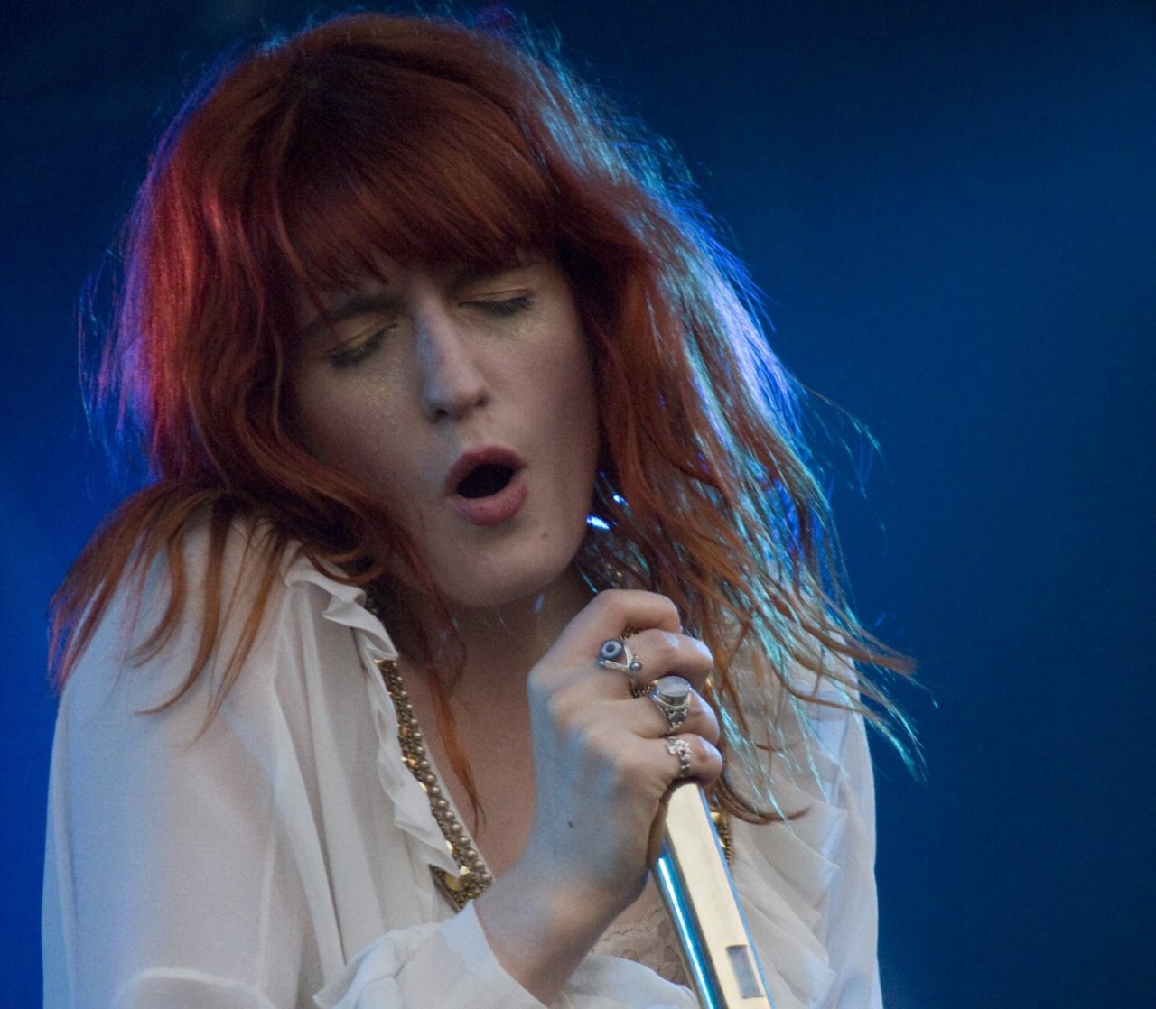 woman with red hair singing into a mic