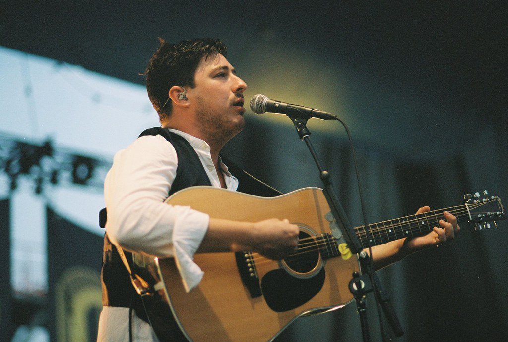 man holding guitar and singing into microphone